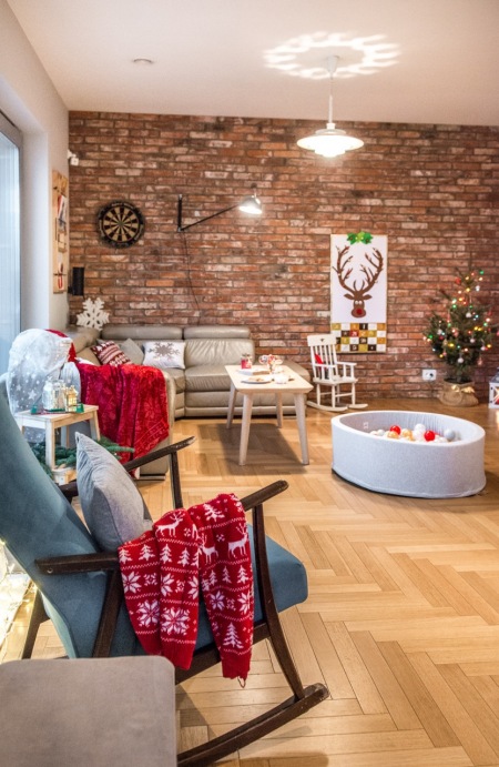 Salon z drewnianą podłogą, czerwoną cegłą i świątecznymi dodatkami