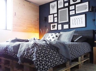 Oryginalna aranżacja sypialni opiera się na ciemnej palecie barw i elementach drewna. Na granatowej ścianie wisi bogata...
