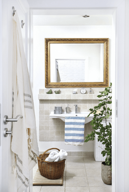 Biała łazienka z szarymi płytkami i ze stylowym rzeźbionym lustrem w złotych ramach