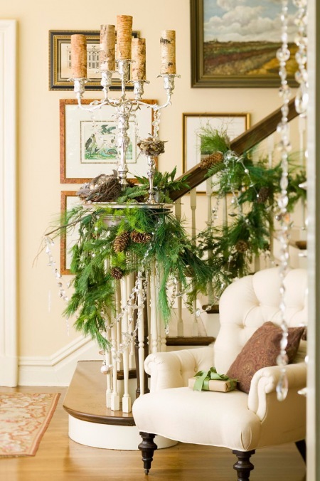 Pięcioramienny srebrny świecznik,szklane girlandy i zielone gałązki w dekoracji stylowych schodów