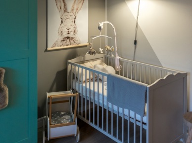 Obok niebieskiej szafy, w rogu pomieszczenia znalazło się małe łóżeczko dla niemowlęcia. Ta część pokoiku dziecięcego utrzymana jest w chłodniejszej kolorystyce szarości i...
