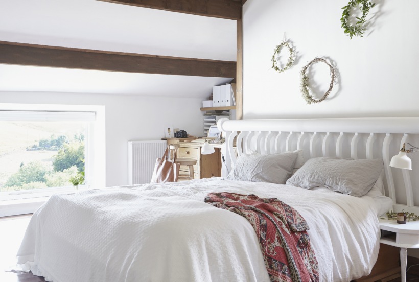 Biała sypialnia z drewnianym belkami na poddaszu