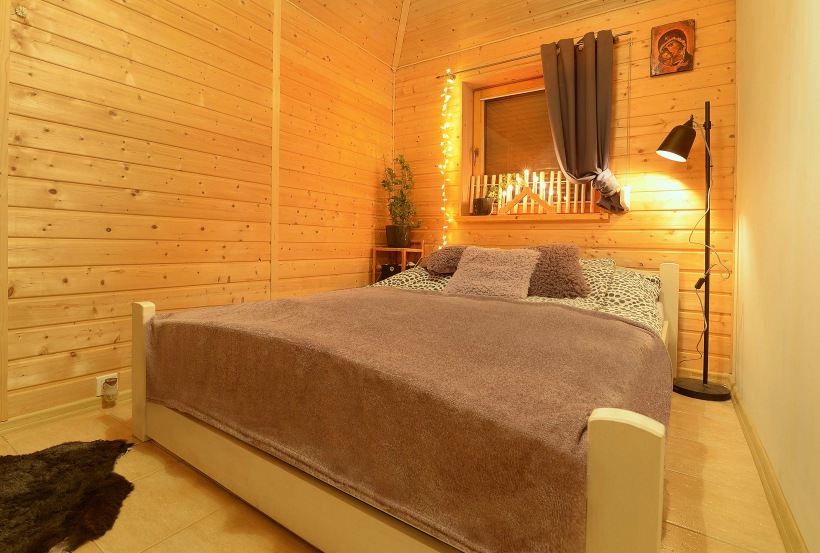 Mała sypialnia z drewnianymi deskami na ścianach i suficie