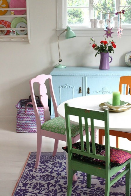 Okrągły bały stół z pomarańczowym, zielonym i różowym krzesłem