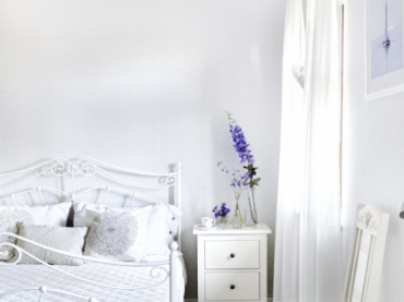 Białe kute łóżko w aranżacji sypialni z bielona podłogą z desek (24838)
