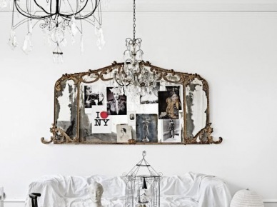 Francuskie rzeźbione ramki z fotografiami jako ozdoba na ścianie nad biała sofą i kutymi żyrandolami z kryształkami (24615)