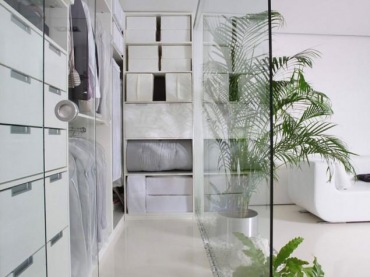 bardzo ciekawy pomysł na aranżację otwartej zabudowy w mieszkaniu - to minimalistyczna dekoracja, gdzie posłużono się bielą i szkłem. Warto zwrócić uwagę na ścianę ze szkła, która łączy i zarazem dzieli salon z garderobą. Znaczącą rolę odegrały tu piękne, zielone rośliny, które utworzone na wzór rabaty, zostały wypełnione białymi...