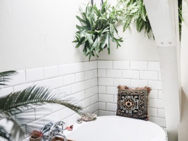 Dzięki roślinom w doniczkach łazienka nabiera wyjątkowych cech. Wanna ze wzorzystą poduszką zachęca do kąpieli i...