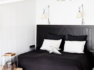 Czarne drewniane łóżko,czarna narzuta,drewniana skrzynia vintage i białe lampy i kinkiety w białej sypialni (27693)