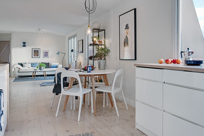 Okrągły stół z białymi nowoczesnymi krzesłami na otwaretej przestrzeni kuchni z salonem