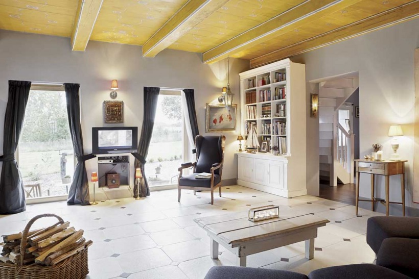 Drewniany sufit,biało-czarna terakota,szare zasłony i fotel w aranżacji salonu