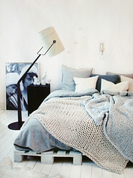 Łóżko na drewnianych paletachw szarej aranżacji sypialni