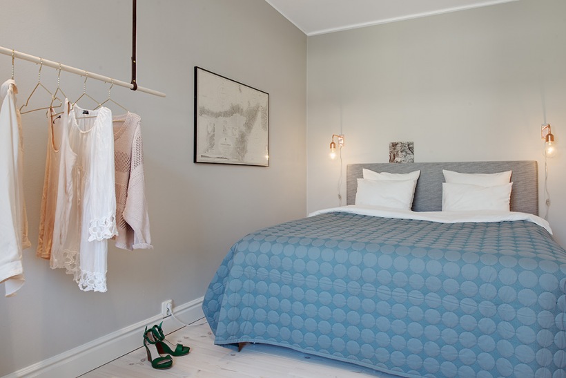 Sufitowy wieszak w aranzacji skandynawskiej sypialni z niebieska narzutą