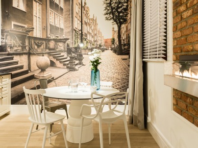 Fototapeta z ulicą Mariacką w Gdańsku stanowi tu tło dla jadalni i kuchni. Pomieszczenie utrzymane w kolorach brązowym, białym, czarnym i szarym doskonale współgra kolorystycznie z...