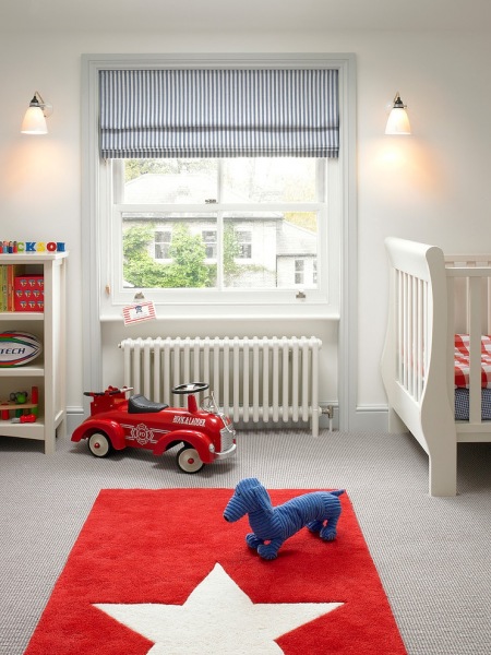 Czerwony dywanik i biało niebieskie rolety w pokoju dziecięcym