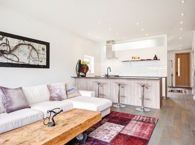 Industrialny drewn iany stolik na kółkach,dywan patchwork i biala sofa w aranzacji otwaetej przestrzeni salonu z kuchnią (25129)