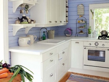 Małą kuchnię o tradycyjnym wyglądzie urozmaicono ścianą pomalowaną na niebieski odcień. Kolorowe deski przykuwają do...