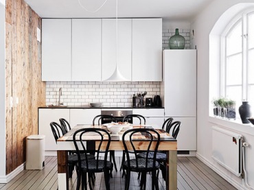 Drewniana ściana w kuchni, idealnie dociepla nowoczesne szafki kuchenne. Świetny m zabiegiem są czarne krzesła, dodają ogromnego...
