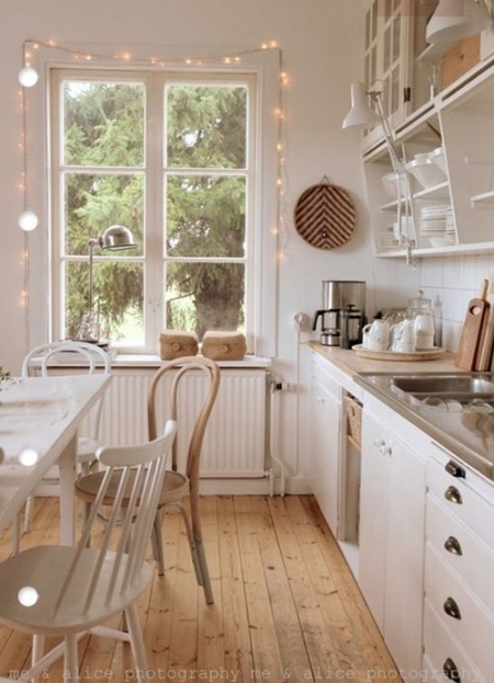 Świecące girlandy wokół okna w białej kuchni
