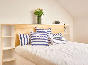 Na łóżku znajduje się kilka poduszek, które upiększają przestrzeń. Niebieski kolor wprowadza nieco ożywienia i...