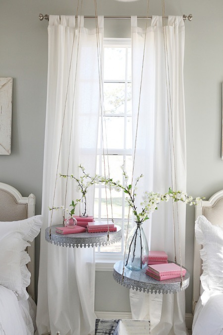 Firany z białego woalu na szelkach i wiszące stoliki z blacy w aranżacji romantycznej sypialni