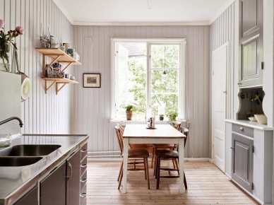 Drewniane półęczki,szara boazeria,biały stół zdrewnianym blatem w aranzacji skandynawskiej kuchni z rustykalnymi detalami (24687)
