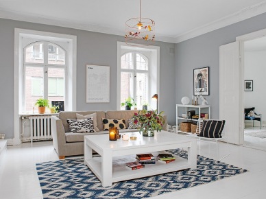 Biały stolik kawowy z półka,beżowa sofa,niebiesko-biały dywan i szare ściany w aranżacji salonu skandynawskiego (26985)
