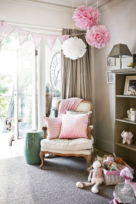 Białe i różowe pompony z tiulu,jasno-różowa girlanda z proporczyków w stylowej aranżacji szarego pokoju dla dziecka