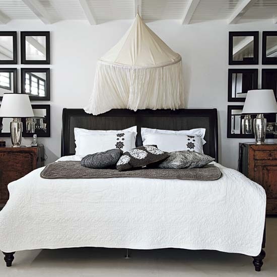 Czarne łóżko z baldachimem i galeria luster w sypialni