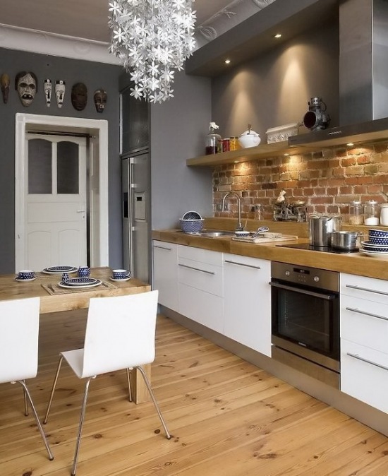 Nowoczesna biała kuchnia z detalami ze stali,szarymi i ceglanymi ścianami i drewnianą podłogą