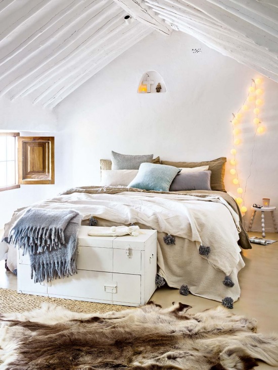 Biała sypialnia na wysokim poddaszu z drewnianymi belkami pod sufitem