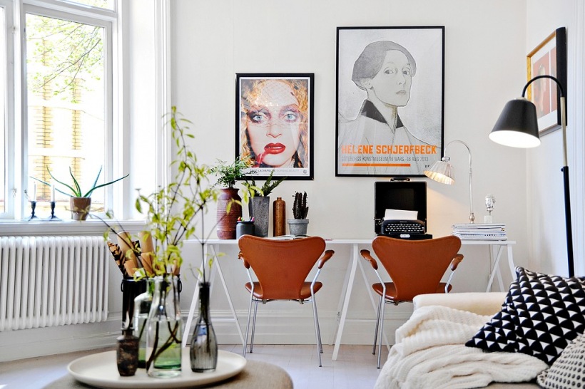 Białe biurko skandynawskie,brązowe krzesła i współczesne grafiki w pokoju biurowym