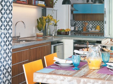 Przecierany stół w kolorowej kuchni, gdzie żółte i błękitne dodatki dodają energicznej atmosfery.