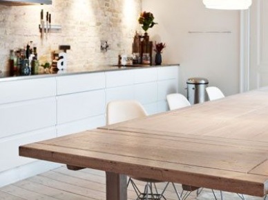 Nowoczesna kuchnia z białymi szafkami,stalowym okapem,ścianą ze starzonej czerwonej cegły i drewnianym dużym stołem (25281)