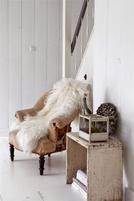 Beżowy fotel vintage,patynowany drewniany stołek,biały futrzak przy drewnianych malowanych na biało schodach