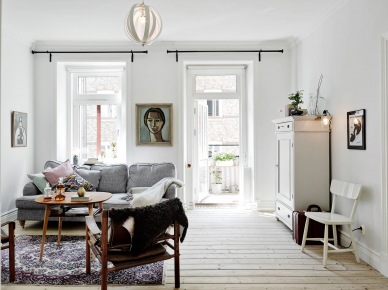 Szara sofa,drewniany okrągły stolik kawowy,drewniany fotel i biała komoda vintage w salonie (25726)