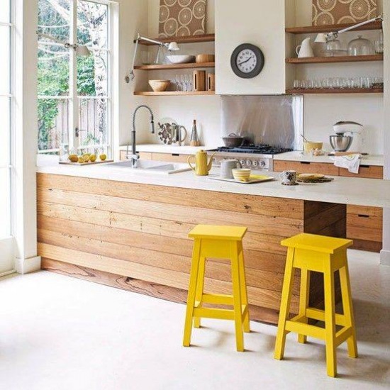 Żółte stołki przy kuchennej ladzie z drewna  z białym blatem