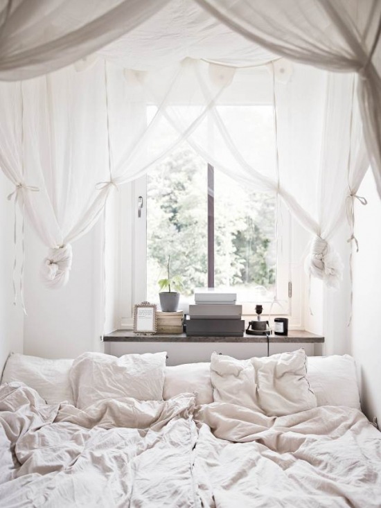 Biały woalowy dekoracyjnie upiety baldachim nad łóżkiem w sypialni