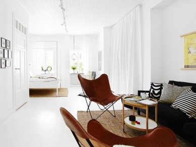 Czarna sofa,brązowe fotele butterfly i drewniany stolik w aranżacji salonu z białą podłoga i ścianami (24654)