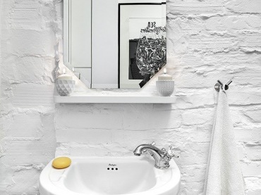 Niezwykle prosta i jasna łazienka. Jako tło do nowoczesnych akcentów, takich jak proste lustro, umywalka czy uchwyt na ręcznik, wykorzystano ścianę z pomalowanych na biało...