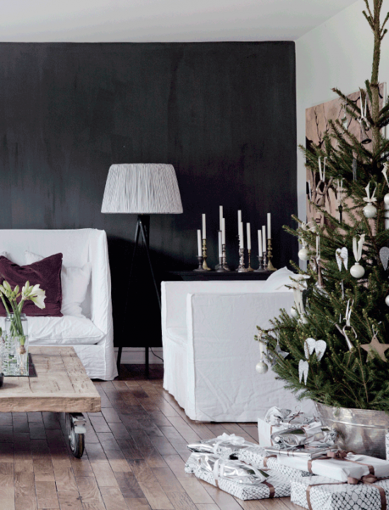 Białe sofy i fotele w lnianych pokrowcach,czarna ściana,stolik z palety na kółkach,zielona choinka w białych dekoracjach świątecznych