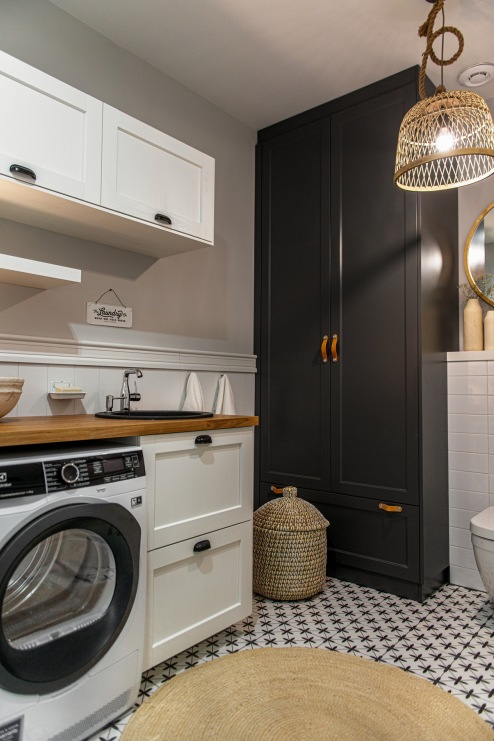 W aranżacji łazienki połączonej z pralnią znajduje się wyraźny, czarny element, który stanowi duża szafa. Dzięki niej...