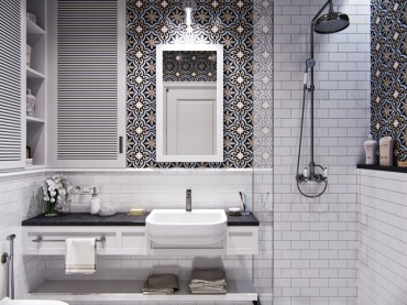 Aranżację białej łazienki urozmaicają wzorzyste kafle na ścianie. Strefę prysznica od reszty pomieszczenia oddziela...