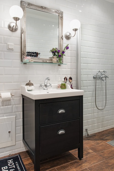 Biała płytka glazurowana cegiełka na ścianie w łazience z duzym stylowym szarym lustrem i czarną szafką pod umywalką