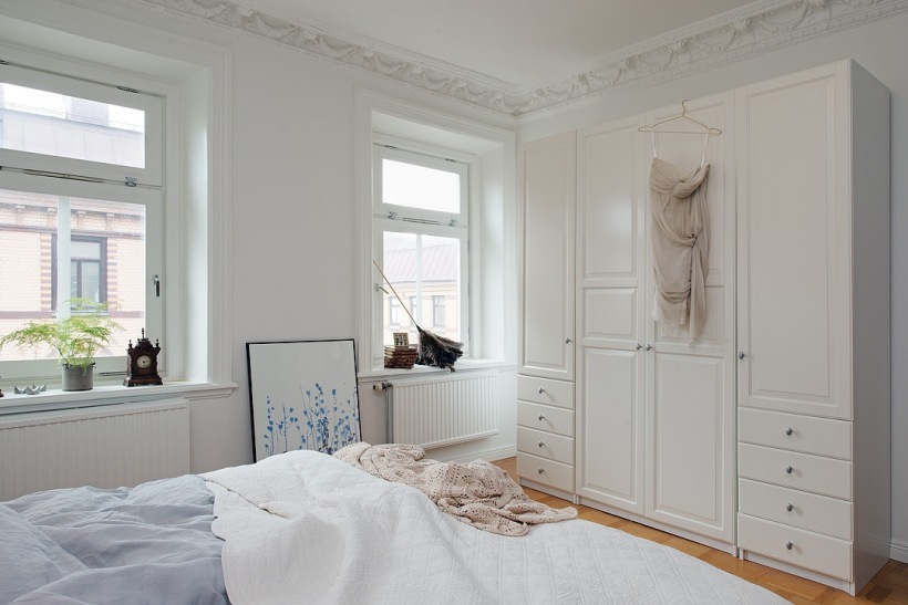 Białe szafy z szufladami w aranżacji skandynawskiej sypialni