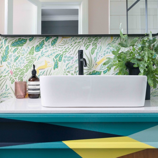 Liściasta tapeta i kolorowa szafka w eklektycznej łazience