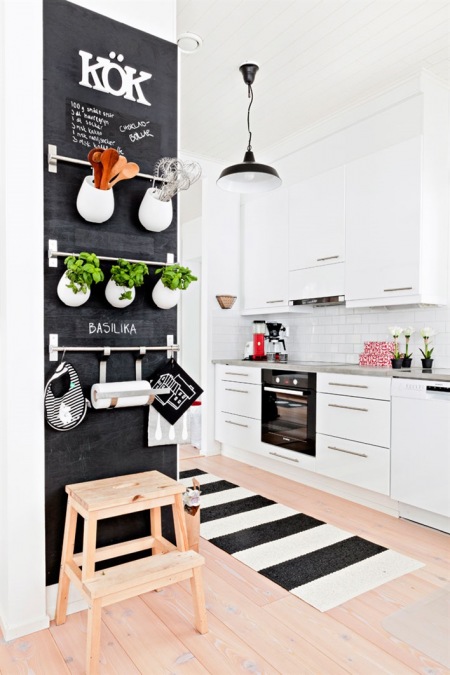 Czarna farba tablicowa na ścianie z pólkami w kuchni
