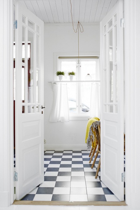 Dwuskrzydłowe białe drzwi z przeszkleniem w aranżacji jadalni z podłogą w czarno-białą szachownicę