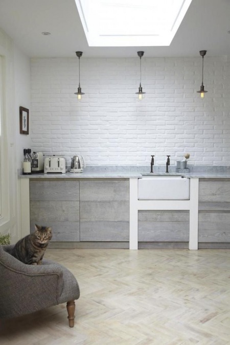 Szara minimalistyczna kuchnia w stylu industrialno-rustykalnym  z białą cegła na ścianie i czarnymi metalowymi lampami