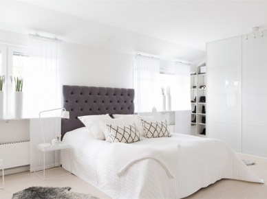 Biała sypialnia z czarnym pikowanym zagłówkiem,nowoczesnymi wazonami na oknie i graficznymi klasycznymi poduszkami (28637)